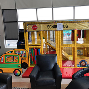 The image shows an indoor play area with a colorful bouncy castle, slide, and climbing structure designed for children.